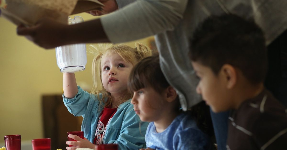 A girl reaching up with a quart of milk