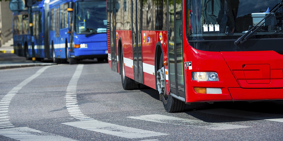 A blue bus behind a red bus