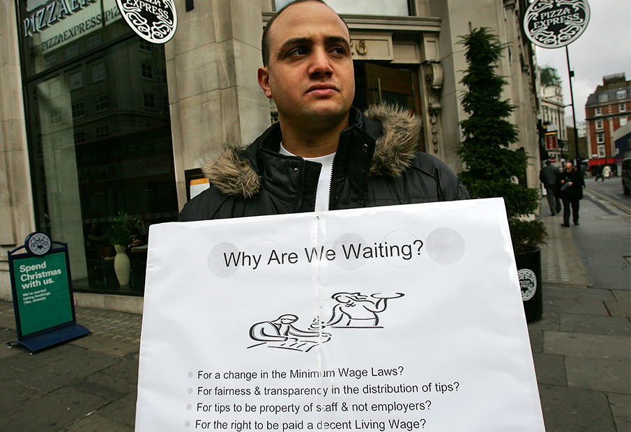 a man holding a sign that says why are we waiting?