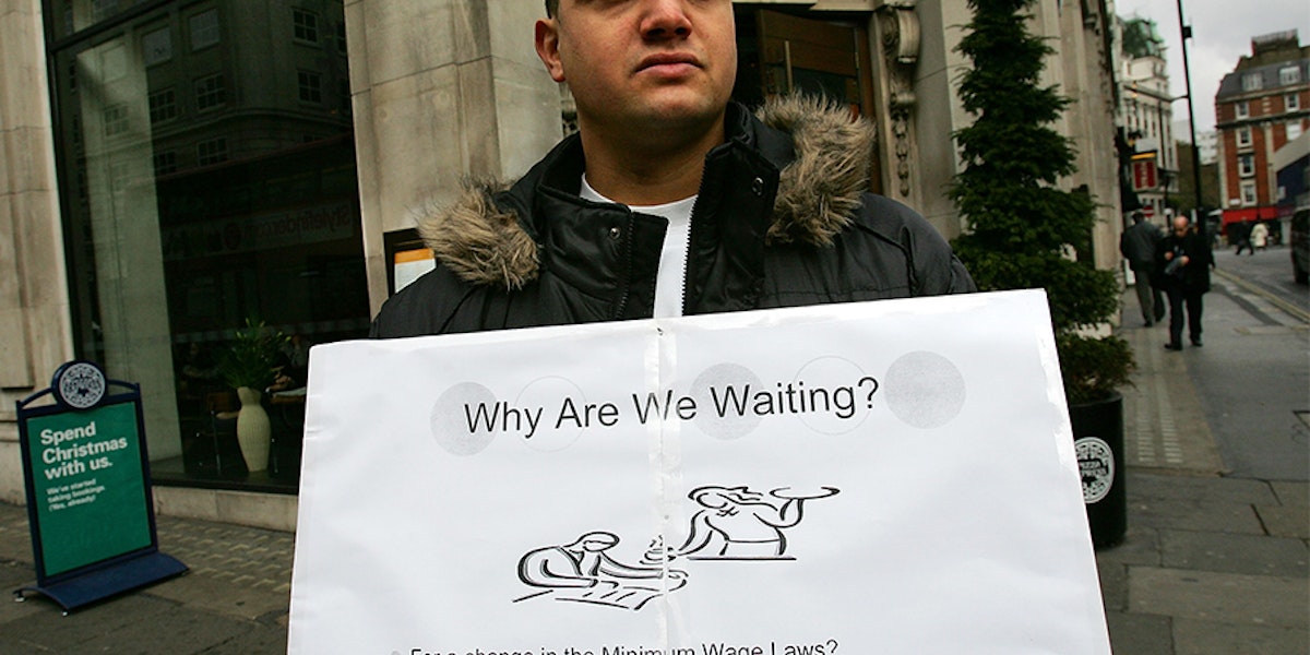 a man holding a sign that says why are we waiting?
