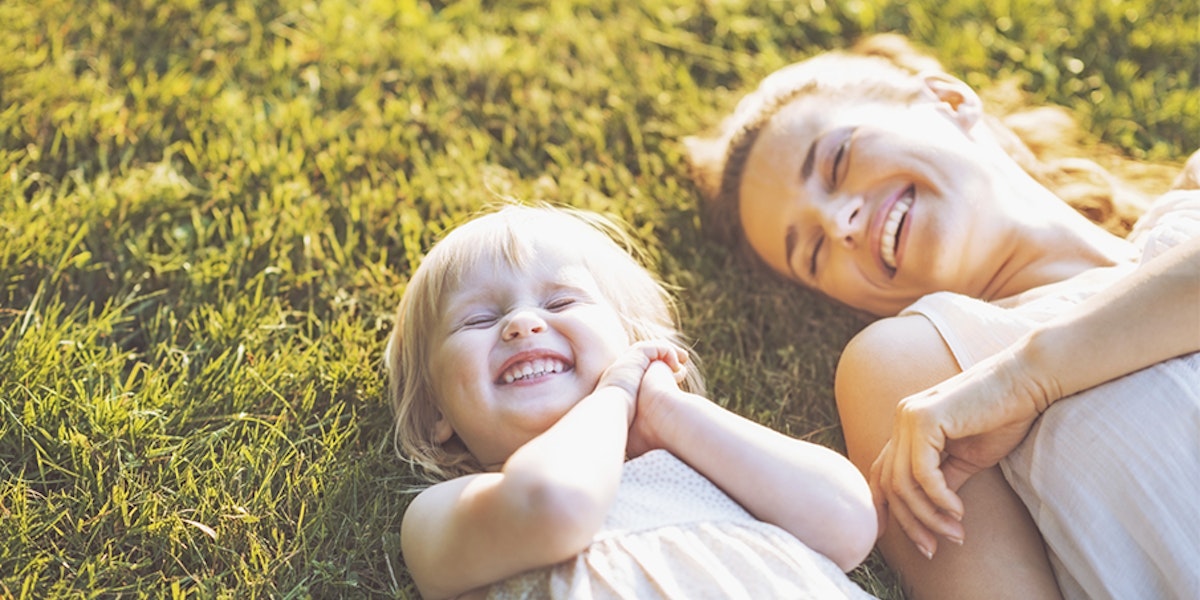 Two girls lying down and smiling on grass