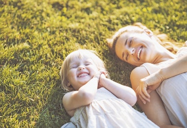 Two girls lying down and smiling on grass