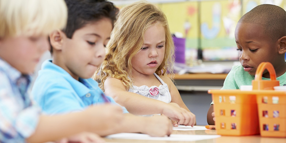 Four multicultural students in a classroom coloring