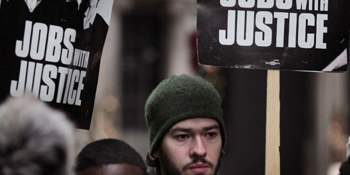 Man holding a jobs with justice sign