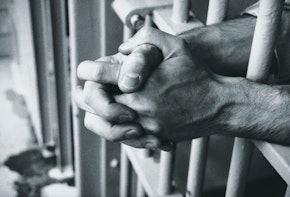 Hands clasped behind bars