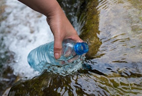 a person is holding a water bottle in the water