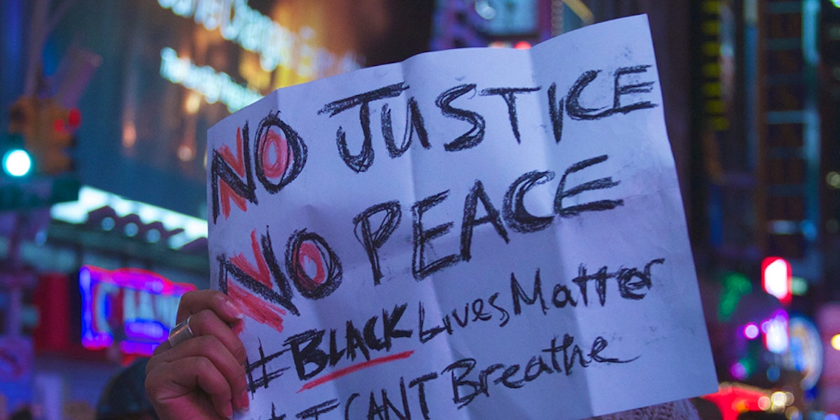 a person holding a sign that says no justice no peace