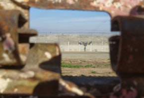 a pov of looking through a crack facing out to a jail fence