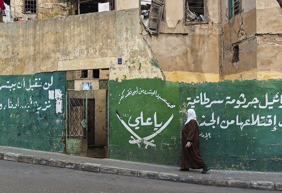 a woman walking down a street past a building
