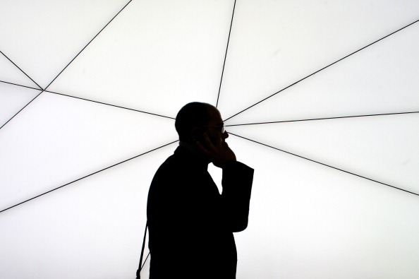 BARCELONA, SPAIN - FEBRUARY 25:  A visitor talks on his mobile phone as he walks past a Samsung stand during the first day of the Mobile World Congress 2013 at the Fira Gran Via complex on February 25, 2013 in Barcelona, Spain. The annual Mobile World Congress hosts some of the world's largest communication companies, with many unveiling their latest phones and gadgets. The show runs from February 25 - February 28.  (Photo by David Ramos/Getty Images)