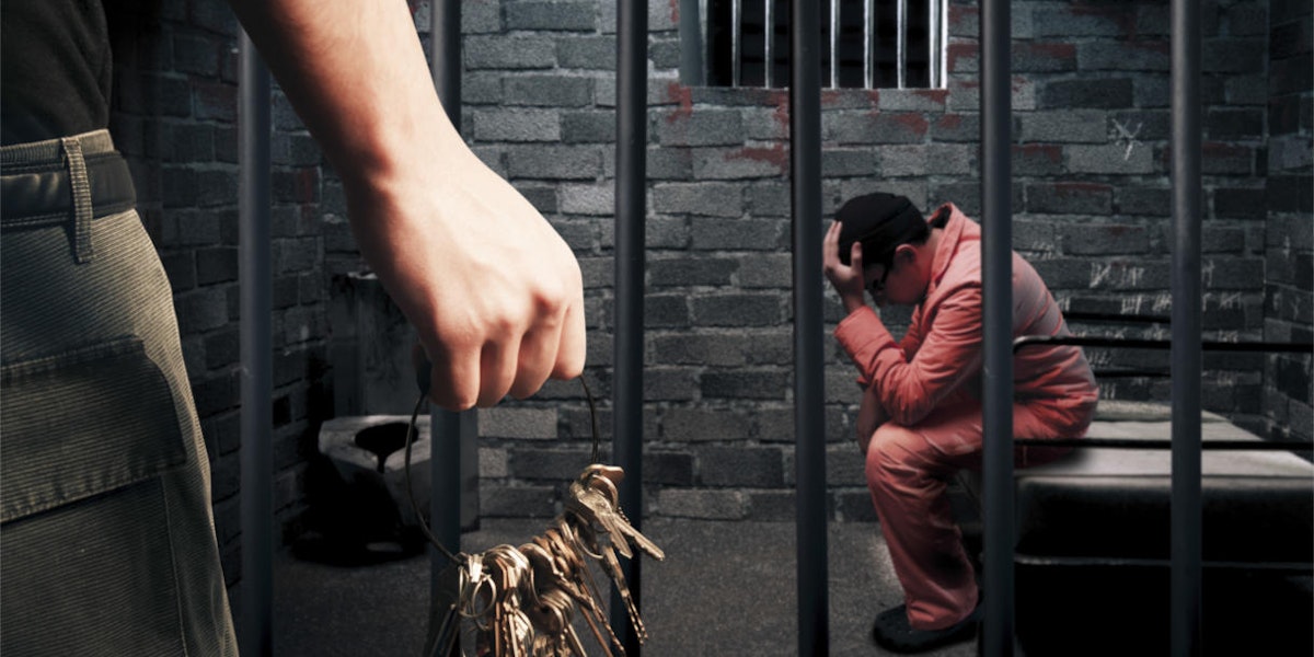 a man sitting on a bench in a jail cell