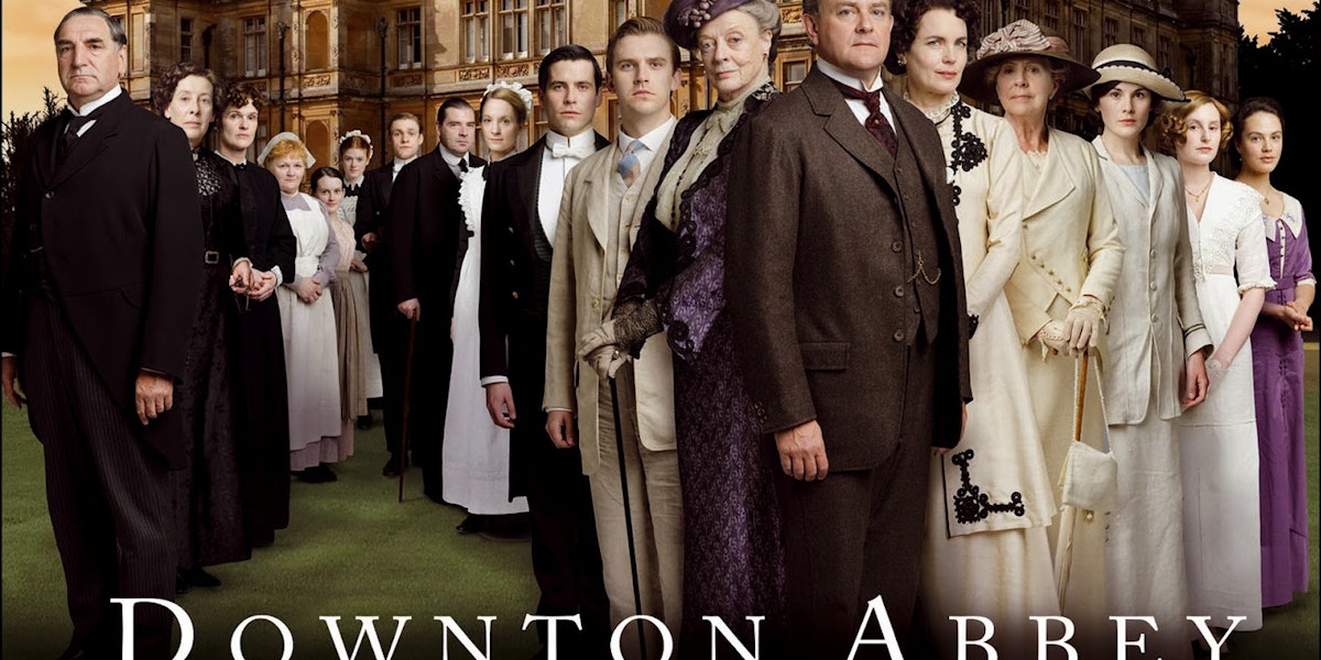 A Poster of Downtown Abbey of people dressed formerly in an array in front of a castle.