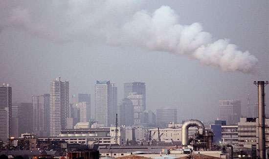 smoke billows from a factory in a city