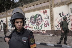 CAIRO, EGYPT - DECEMBER 14:  Soldiers stand guard in front of the presidential palace as anti-scaf graffiti is seen on the wall on December 14, 2012 in Cairo, Egypt. Opponents and supporters of Egyptian President Mohamed Morsi staged final rallies in Cairo ahead of tomorrow's referendum vote on the country's draft constitution that was rushed through parliament in an overnight session on November 29. The country's new draft constitution, passed by a constitutional assembly dominated by Islamists, will go to a referendum vote on December 15.  (Photo by Daniel Berehulak/Getty Images)