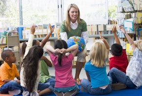 Photograph of a teacher sitting with toddler students