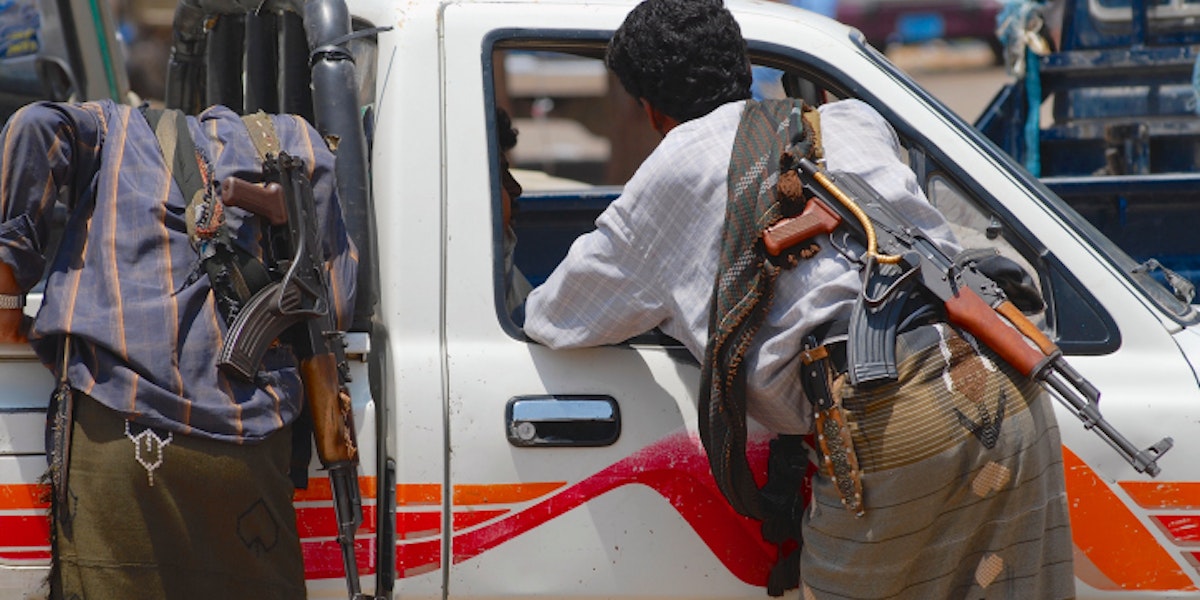 Yemeni people with Kalashnikov guns talk to a car driver.