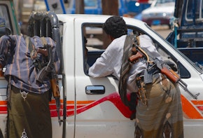 Yemeni people with Kalashnikov guns talk to a car driver.