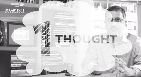 a man sitting at a table in front of a book shelf