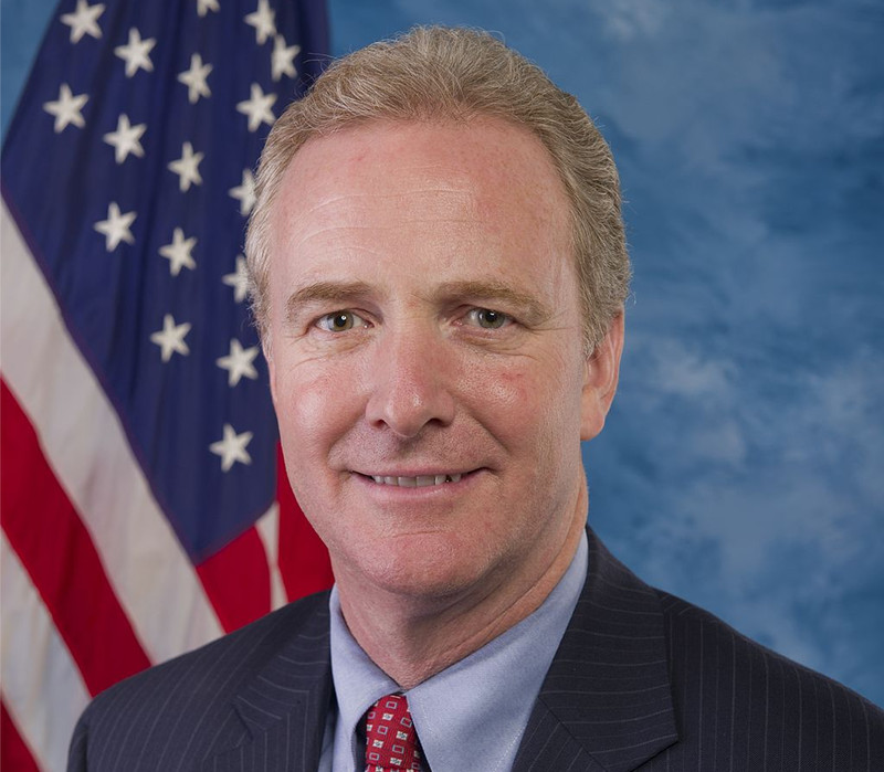 a man in a suit and tie in front of an american flag