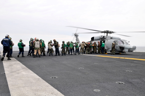 Sailors and Marines load supplies onto a HH-60H Seahawk.