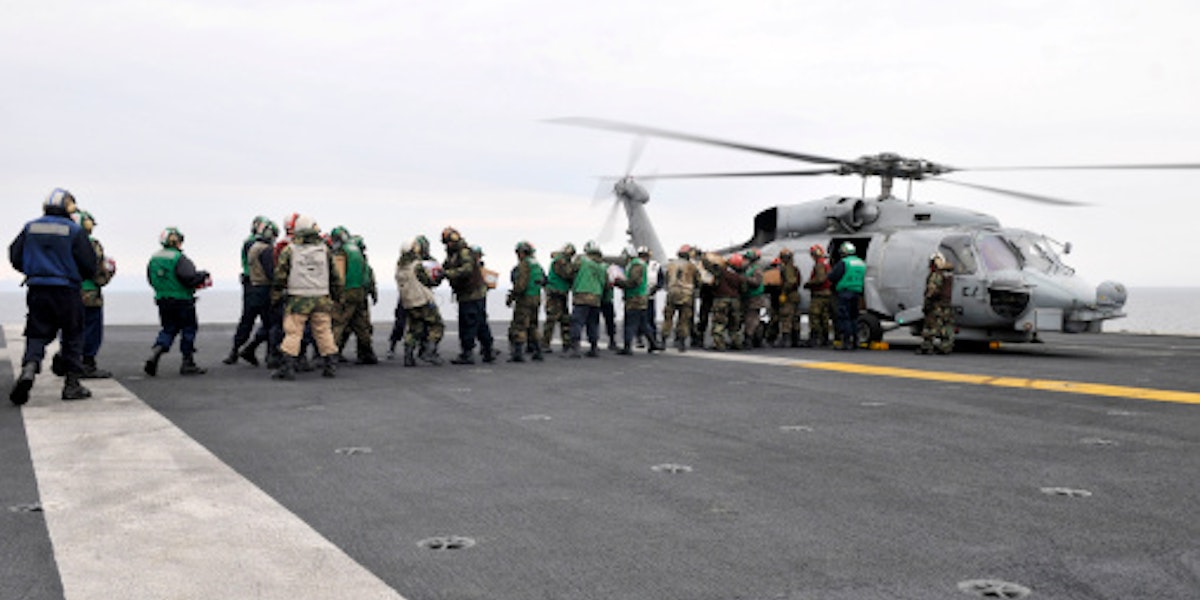 Sailors and Marines load supplies onto a HH-60H Seahawk.