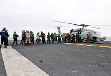 Sailors and Marines load supplies onto a HH-60H Seahawk.
