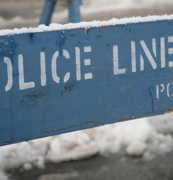 a blue police line sign sitting on the side of a road