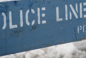 a blue police line sign sitting on the side of a road