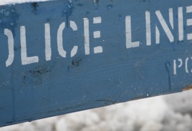 a blue police line sign sitting on the side of a road