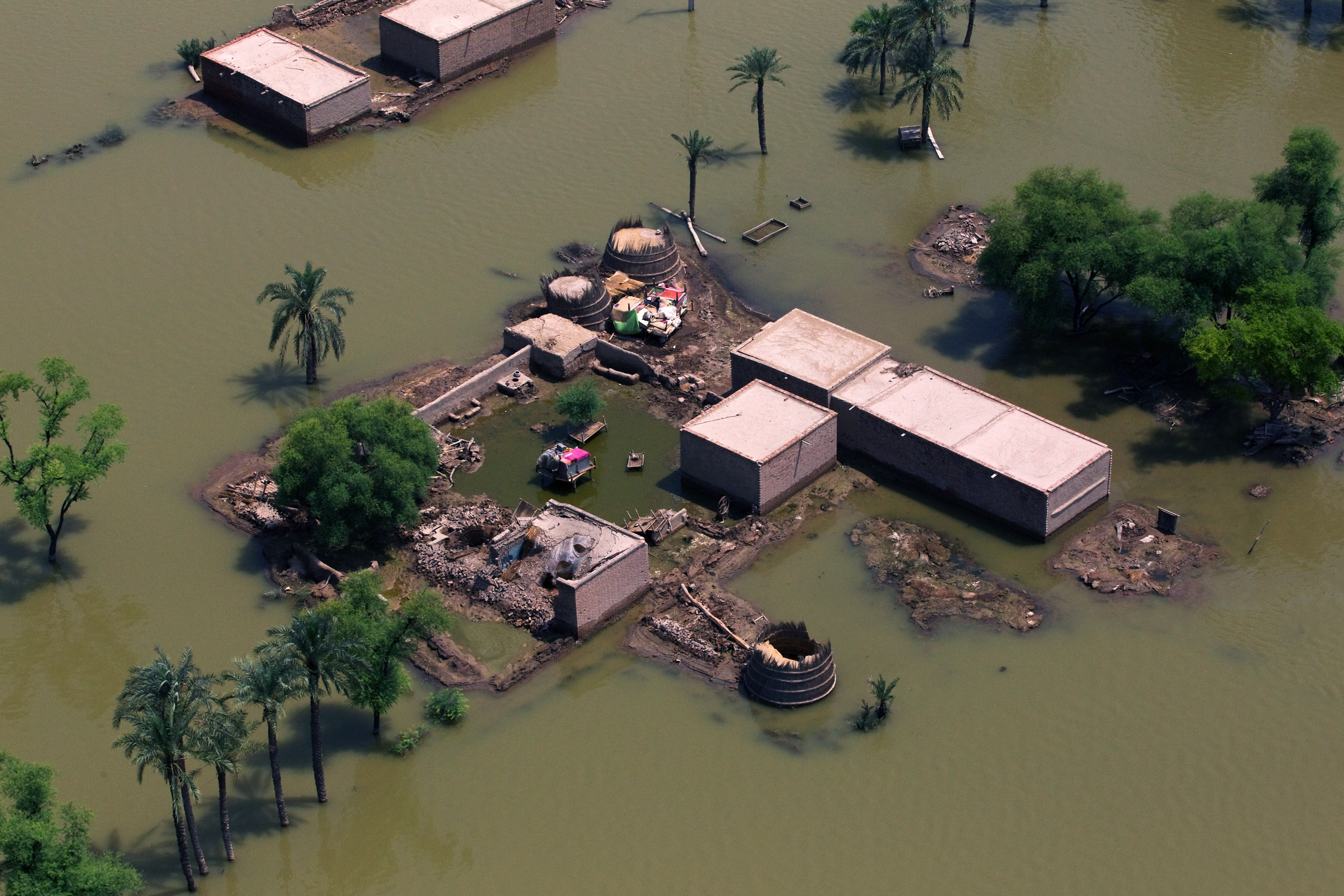 IN AIR, MUZAFFARGARH, PAKISTAN - AUGUST 22: Flood victims scamper for aid relief dropped by a Pakistan Army helicopter on August 22, 2010 in the village of Shah Jamaal west of Muzaffargarh in Punjab, Pakistan. The country's agricultural heartland has been devastated, with rice, corn and wheat crops destroyed by floods. Officials say as many as 20 million people have been effected during Pakistan's worst flooding in 80 years. The army and aid organizations are struggling to cope with the scope of the wide spread scale of the disaster that has killed over 1,600 people and displaced millions. The UN has described the disaster as unprecedented, with over a third of the country under water.  (Photo by Daniel Berehulak/Getty Images)