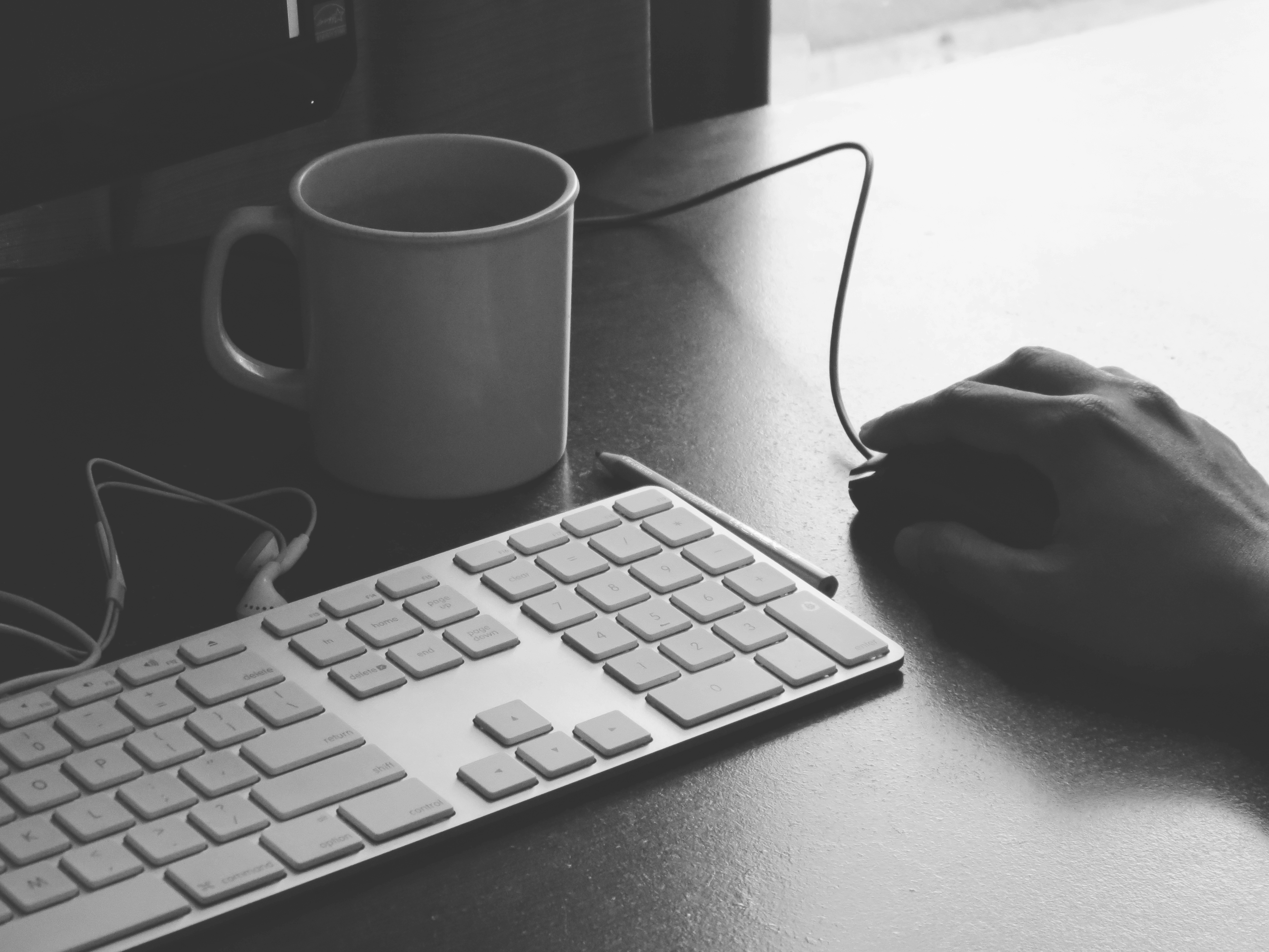 Photograph of a desk with a keyboard, mouse, and coffee