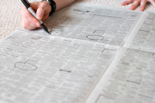 Hand circling ads in newspaper