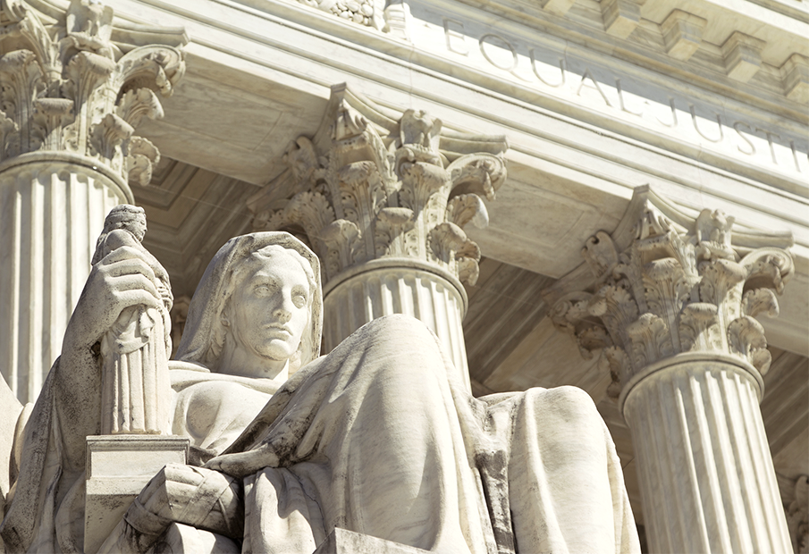 a statue of a woman sitting on a bench in front of a building