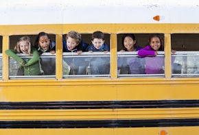 Multi-ethnic elementary school students (5 to 9 years) in school bus, looking out windows.