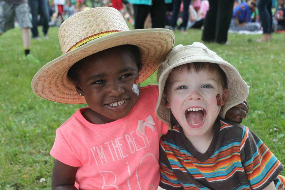 two children sitting on the grass with hats on
