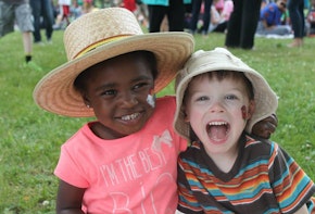 two children sitting on the grass with hats on