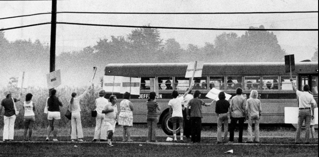 Demonstrators waved signs along Fairdale Road as one bused to Fairdale High School neared its destination. Source: The Courier-Journal.