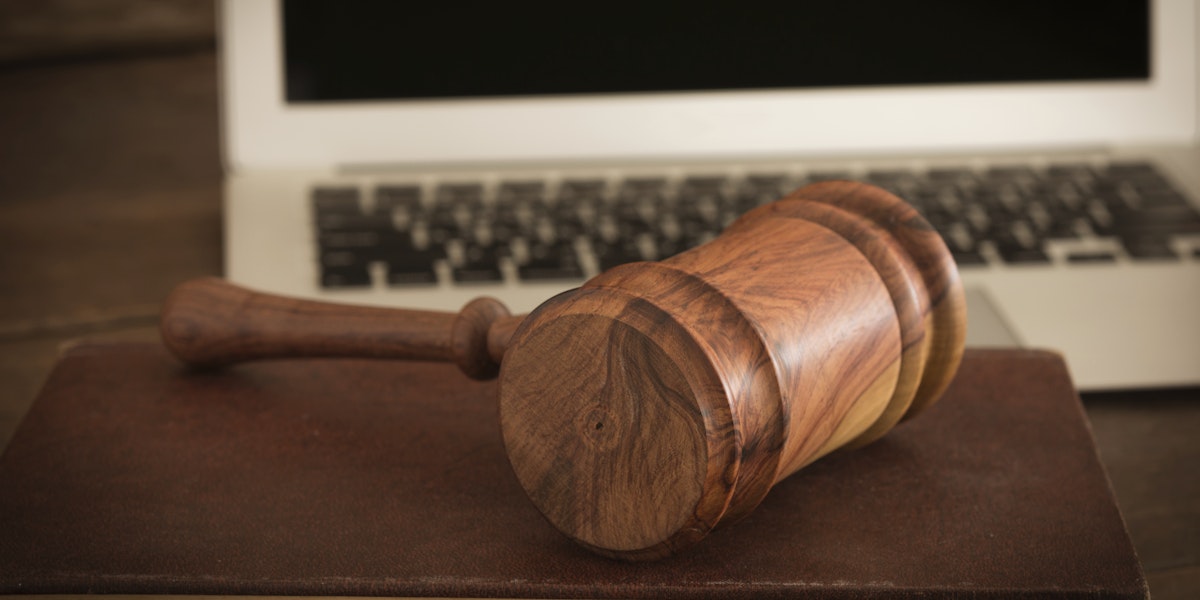 Wooden judge gavel on law book with laptop computer in background. Concept of cyber law or law about internet.