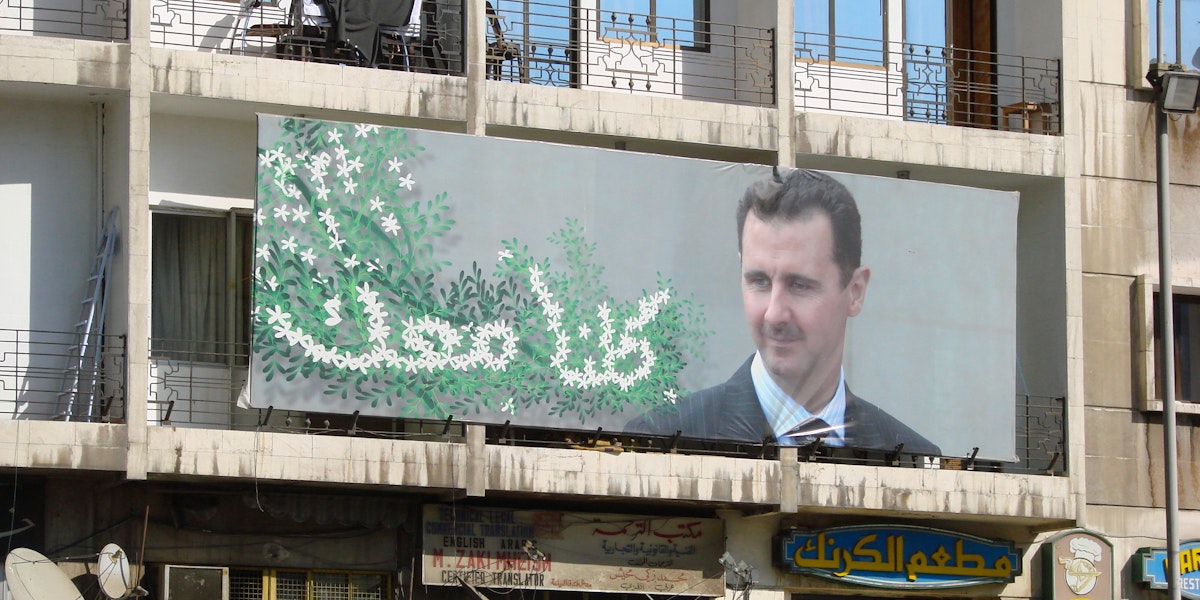 a sign of Bashar al-assad hanging on a building