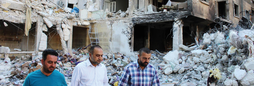 Provincial Council head Ghassan Hammou (left) visits scene of regime bombing in Idlib city.