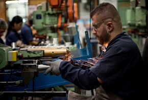 Latin American man working at a factory cutting metal