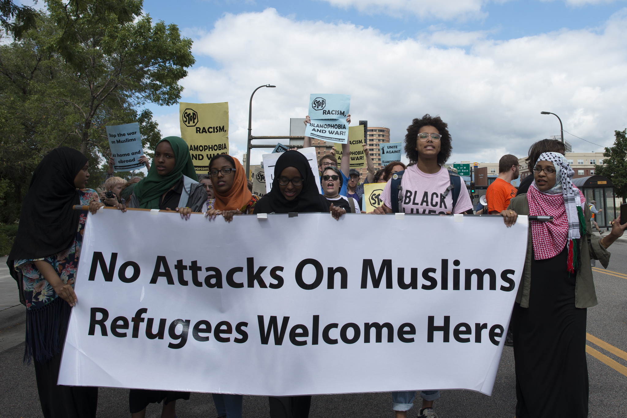 a group of people holding a sign that says no attacks on muslims refugees welcome