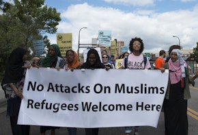 a group of people holding a sign that says no attacks on muslims refugees welcome