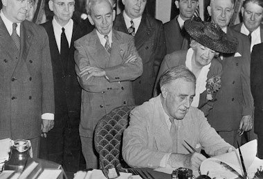 a group of men in suits and ties standing around a table