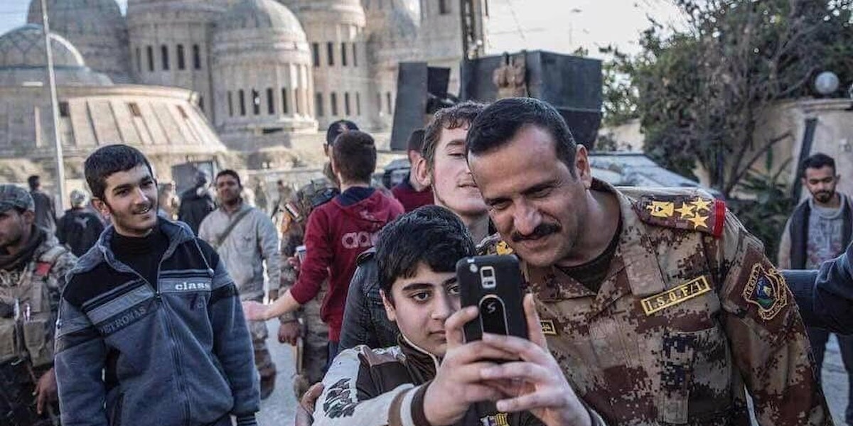A member of the Iraqi National Army poses for a photo with a young resident of Mosul.