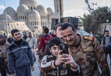 A member of the Iraqi National Army poses for a photo with a young resident of Mosul.
