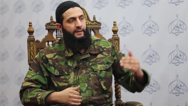 a man with a beard sitting in a chair
