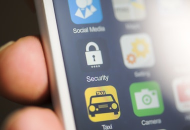 Hand holding phone, security app on screen.