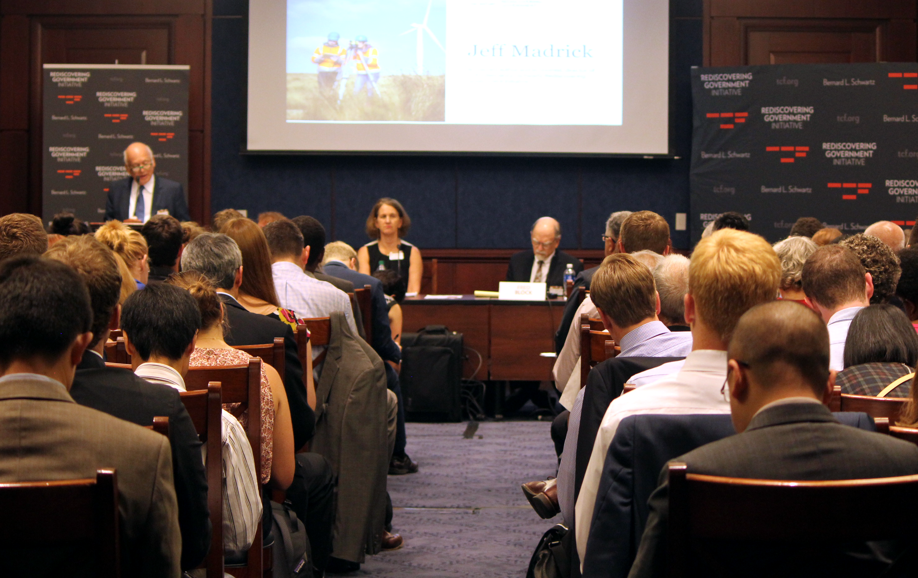 a group of people sitting in chairs in front of a projector screen
