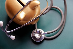 Piggy bank with Doctor’s stethoscope on green wooden board. This photo may use as financial background.